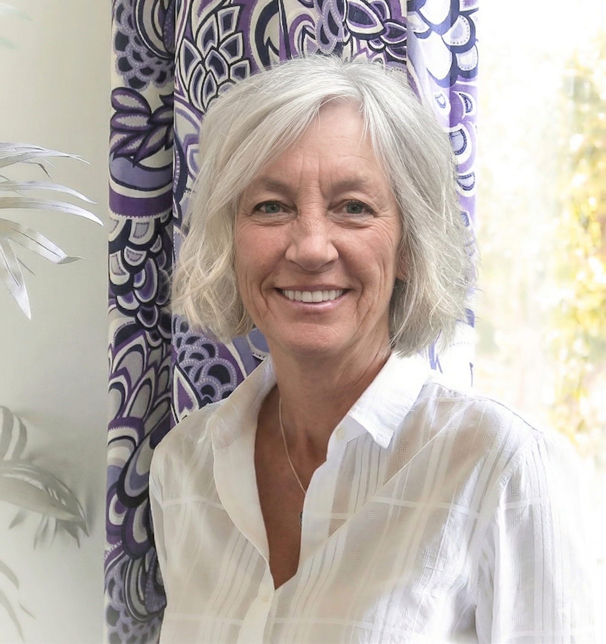 Portrait of Else Johnson standing in front of a purple panel with large abstract floral pattern